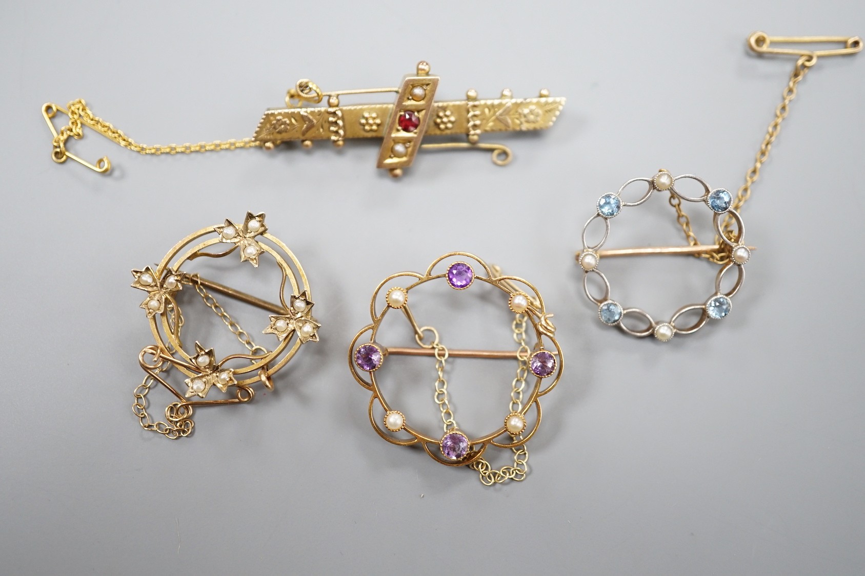 A late Victorian 9ct gold and gem set bar brooch, 43mm and a 9ct and seed pearl set open work brooch, gross 6 grams, a yellow metal amethyst and seed pearl brooch, gross 4 grams and a 15ct, aquamarine and seed pearl set
